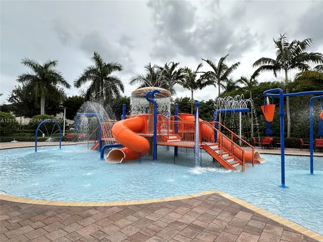 Water park area featuring an expansive pool, multi-level structure with integrated slides, overhead water spray features, and paved decking