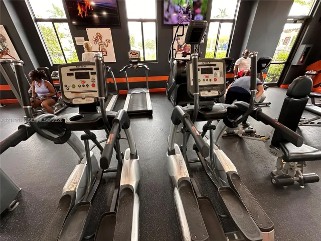 Fitness center featuring rubber flooring, floor-to-ceiling windows, and multiple elliptical and treadmill machines