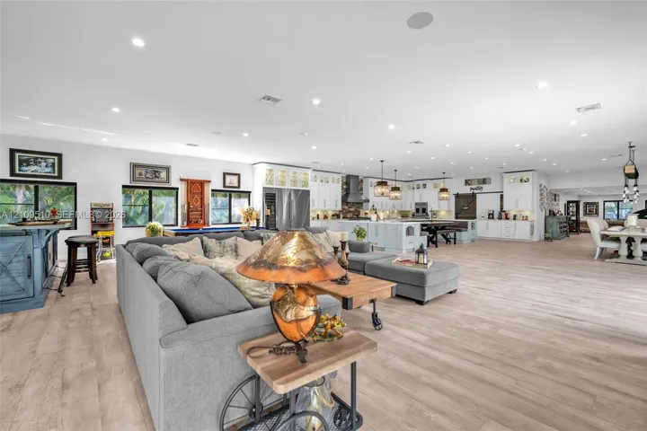 Open-concept interior featuring light wood-finish flooring, recessed lighting, and white cabinetry