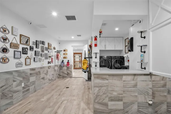 Utility area featuring wood-finish flooring, stone-tiled wall accents, recessed lighting, and white cabinetry with a quartz countertop