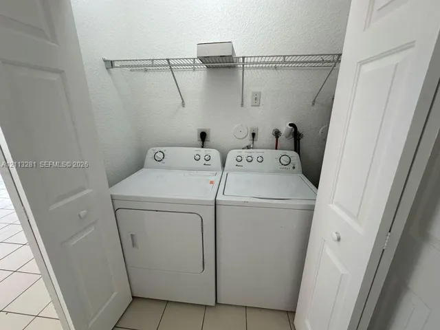 Laundry closet featuring dual bifold doors, tile flooring, and integrated wire shelving