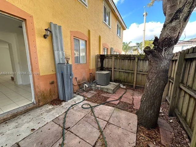 Stucco exterior featuring dual-pane windows, a private concrete patio, and a wood privacy fence