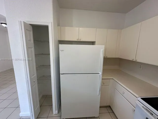 Kitchen area featuring white cabinetry, solid surface countertops, and an integrated pantry with wire shelving