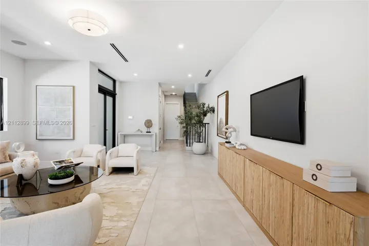 Large-format tile flooring, built-in wooden cabinetry, recessed lighting, and a multi-tiered drum light fixture