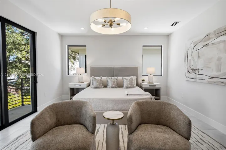 Bedroom featuring large-format tile flooring, a multi-bulb drum pendant light fixture, and black-framed sliding glass doors opening to a balcony