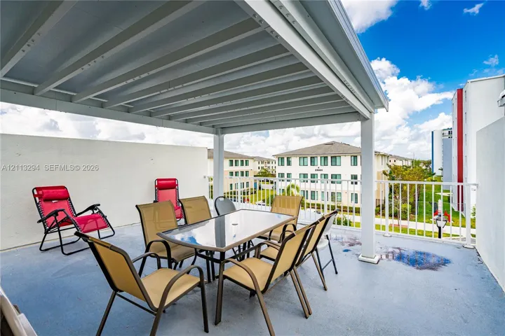 Covered balcony featuring a white metal pergola, solid stucco side walls, and white metal railing