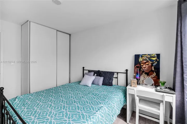 Room featuring neutral wall paint, wood-finish flooring, and a floor-to-ceiling built-in wardrobe with sliding doors