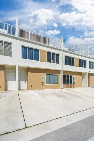 Contemporary multi-level exterior featuring white and tan stucco cladding, horizontal window groupings, a flat roofline, and a private rooftop terrace with metal railings