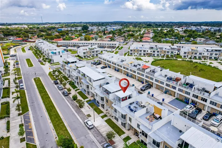 Aerial perspective of a multi-level residential structure featuring a private rooftop terrace, balcony spaces, and paved driveway parking