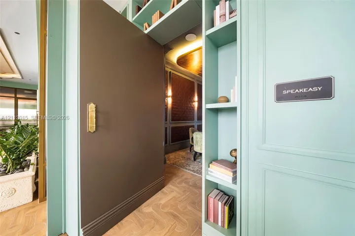 Pivot door with brass hardware, custom built-in cabinetry, herringbone-pattern wood flooring, and recessed ceiling lighting