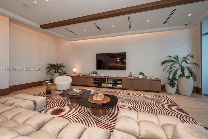 Interior space featuring recessed tray ceiling with integrated perimeter lighting, built-in horizontal cabinetry, wood-finish flooring, and minimalist linear light fixtures