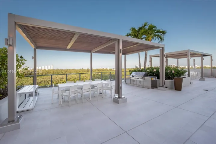 Rooftop terrace featuring large-format tile flooring, metal-framed pergolas with wood-finish ceilings, stainless steel outdoor kitchen, and glass railings