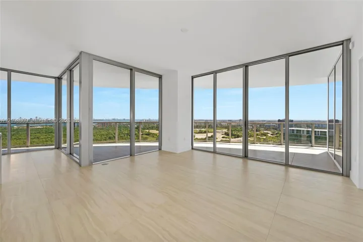 Floor-to-ceiling glass windows with metal frames, wrap-around balcony, neutral tile flooring, and open-plan interior