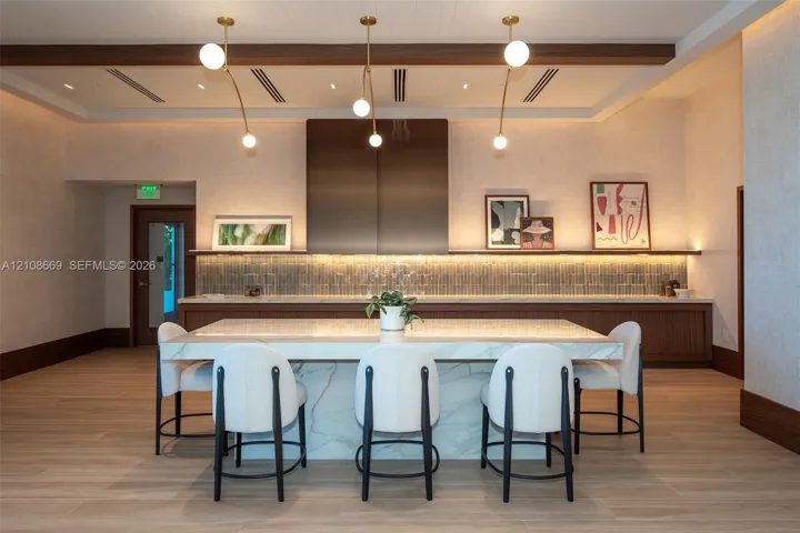 Kitchen featuring a central island with a stone countertop and waterfall edge, metal hood range, linear tile backsplash, wood-finish flooring, and minimalist pendant lighting