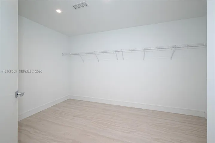 Walk-in closet featuring light wood-finish flooring, recessed lighting, and wall-mounted wire shelving