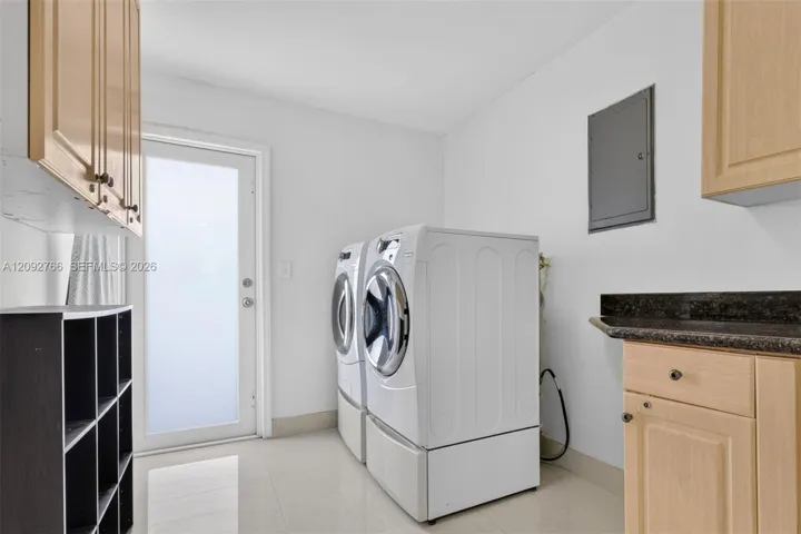 Laundry area featuring light-finish cabinetry, stone-surface countertop, built-in open shelving, and a glass-panel exterior door