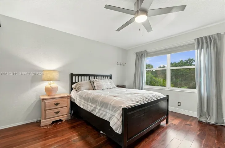 Wood-finish flooring, ceiling fan with integrated lighting, and a window with exterior landscape exposure