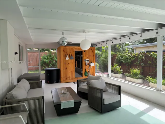 Screened-in patio featuring a vaulted ceiling with exposed beams, wood-paneled sauna, and concrete flooring
