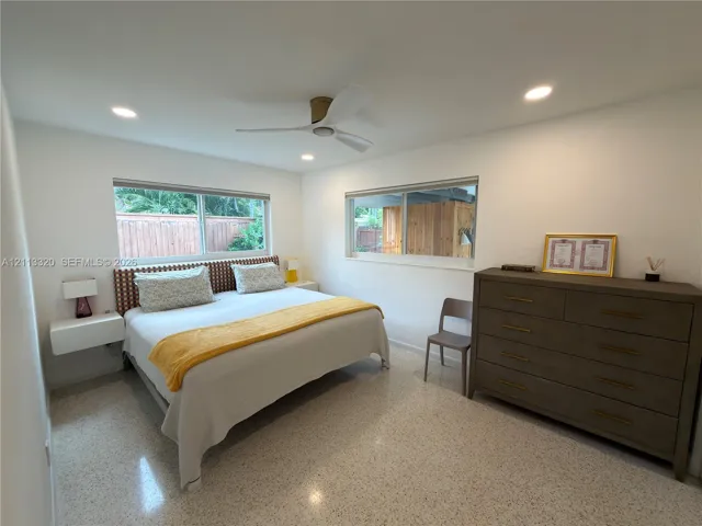 Terrazzo flooring, recessed ceiling lighting, wall-mounted floating bedside tables, and a three-blade ceiling fan