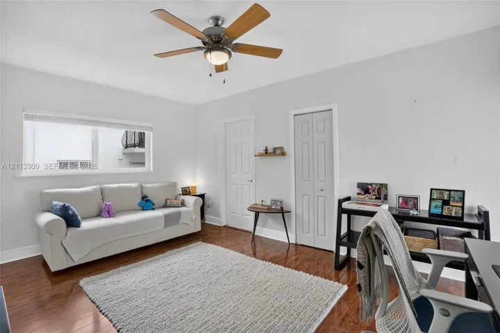 Wood-finish flooring, multi-pane sliding window, ceiling-mounted light fixture with fan, and two-panel interior doors