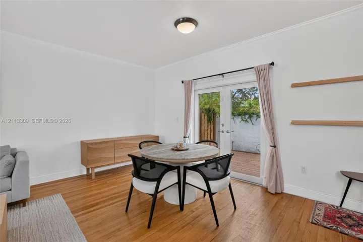 Wood-finish flooring, white walls, dual glass-paneled doors with exterior access, and dual built-in wall-mounted shelves