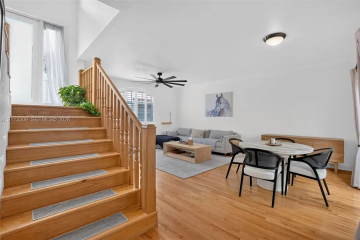 Wood-finish flooring, staircase with a wood balustrade and handrail, vaulted ceiling, and an arched window