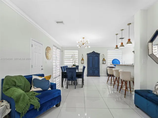 Large-format tile flooring, recessed lighting, crown molding, tiered kitchen peninsula, and multi-light chandelier fixture
