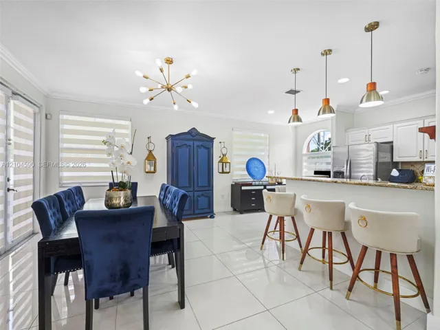 Open-concept space featuring polished tile flooring, kitchen with stone countertops, breakfast bar, multi-arm sputnik chandelier, and recessed lighting