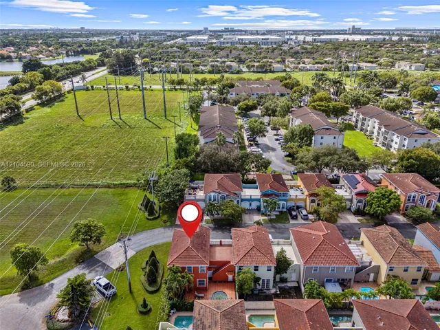 Aerial perspective of a multi-story residence featuring a terracotta tile roof, exterior stucco finish, and a private enclosed courtyard with a swimming pool