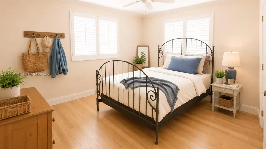 Light-filled room featuring wood-finish flooring, plantation shutters, and a ceiling fan
