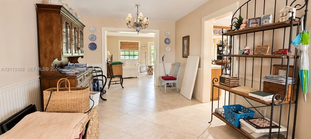 Interior space featuring tile flooring, wainscoting, and a decorative multi-arm chandelier