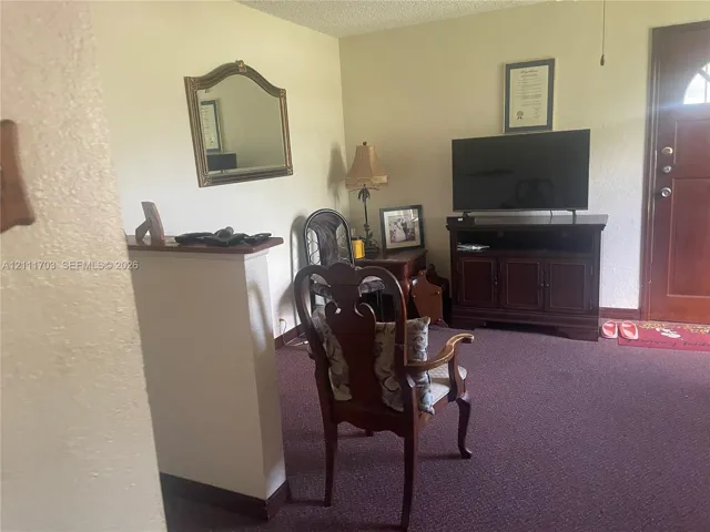 Half-wall room divider, carpeted flooring, and wood-paneled entry door with glass pane