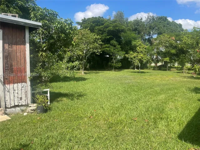 Expansive backyard featuring a grass lawn and mature trees