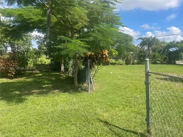 Expansive parcel featuring mature trees, manicured lawn, and chain-link fencing