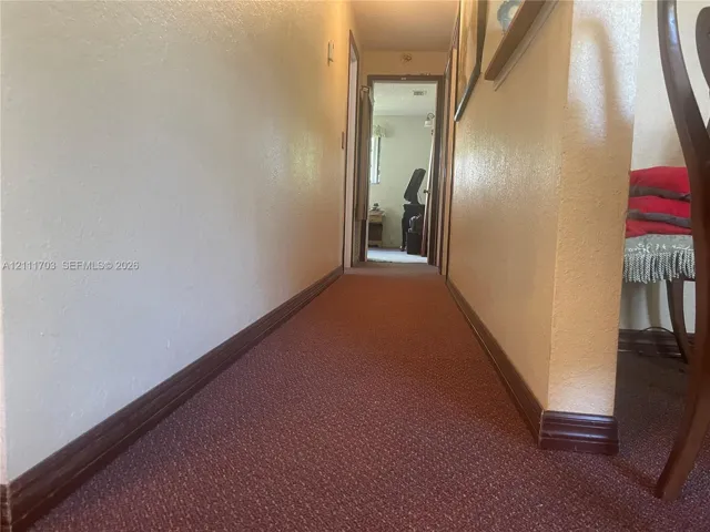 Hallway featuring wall-to-wall carpeting and wood-finish trim