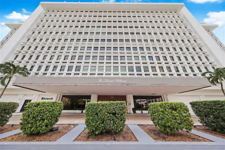 Mid-century modern high-rise exterior featuring a distinctive concrete grid façade, cantilevered entrance canopy, and manicured landscaping