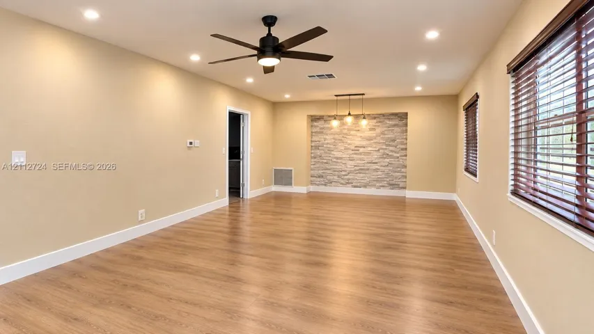 Interior space featuring wood-finish flooring, recessed lighting, a stone-accent wall with pendant fixtures, and a matte black ceiling fan