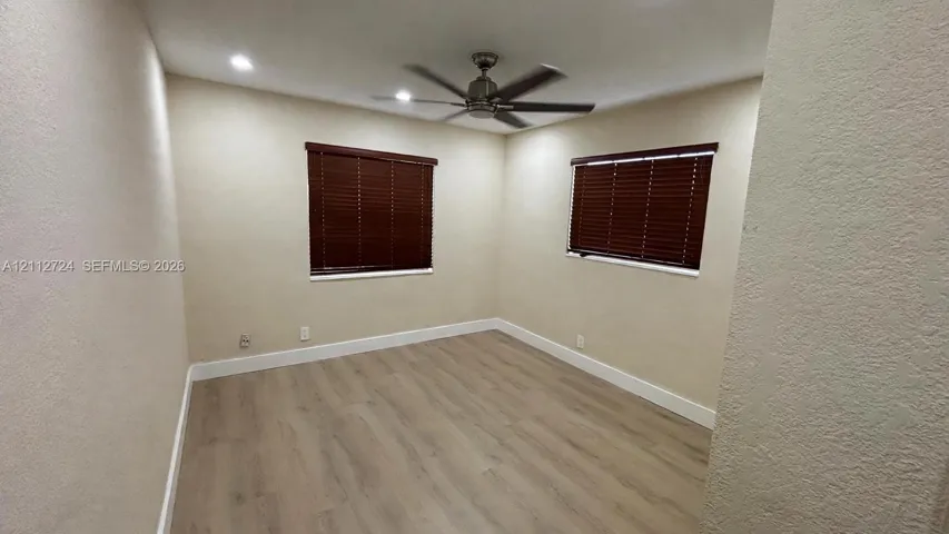 Interior space featuring wood-finish flooring, recessed lighting, a ceiling fan, and windows equipped with fitted blinds