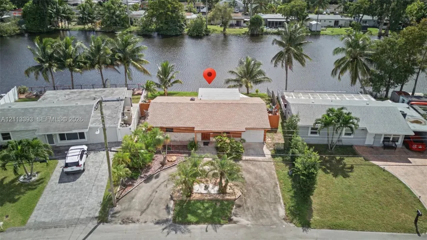 Waterfront property featuring direct canal access, a shingle roof, and mature palm landscaping