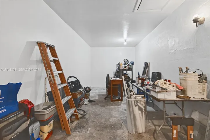 Enclosed storage area featuring white painted walls, a concrete floor, and dual wall-mounted light fixtures