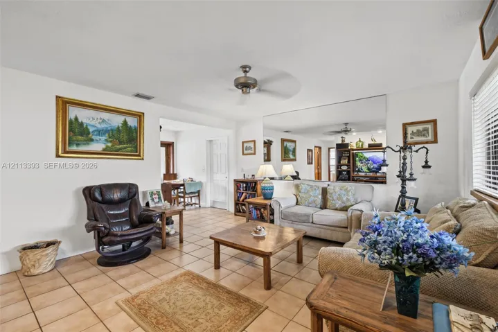 Living area featuring square tile flooring, a ceiling fan, and a large wall-mounted mirror