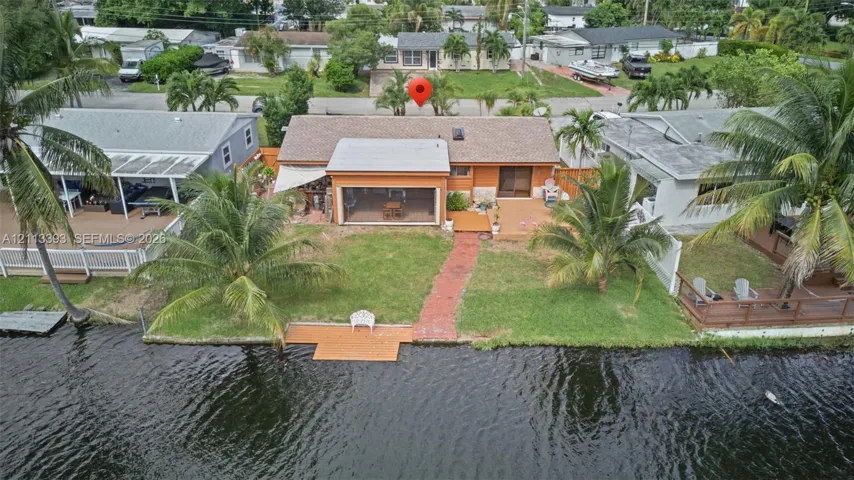 Waterfront residence featuring a screened-in lanai, wood-finish decking, a paved walkway, and direct water access with a private dock