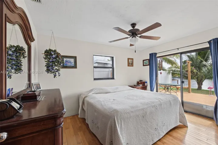 Wood-finish flooring, ceiling fan with integrated lighting, and sliding glass doors with access to an exterior deck