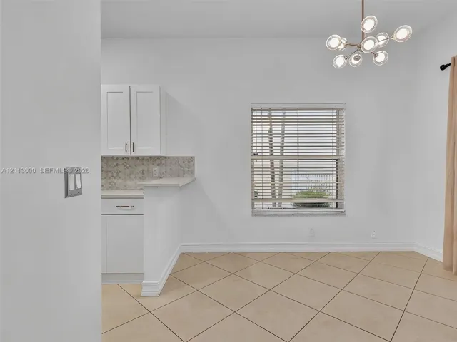 Modern multi-light pendant fixture, white shaker-style cabinetry, mosaic tile backsplash, and diagonal-set tile​​‌​​​​‌​​‌‌​‌‌​​​‌‌​‌​‌​‌​​​‌​​ flooring