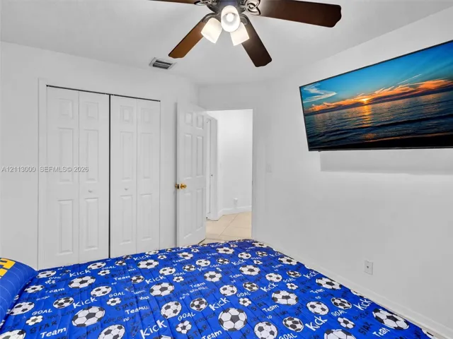 Interior room featuring white walls, a multi-blade ceiling fan with integrated lighting, and a double-door closet