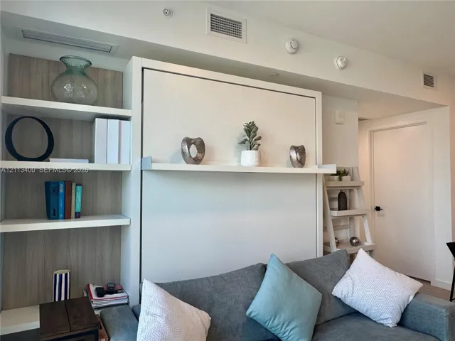 Custom floor-to-ceiling cabinetry featuring integrated shelving with a neutral wood-finish backing and a central fold-down wall unit