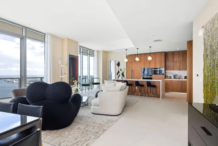 Floor-to-ceiling windows, custom wood-finish cabinetry, built-in panel-ready appliances, stone-topped kitchen island, and large-format tile flooring