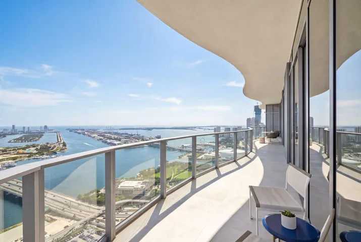 Curved balcony featuring a glass railing system, concrete flooring, and an overhanging structural soffit