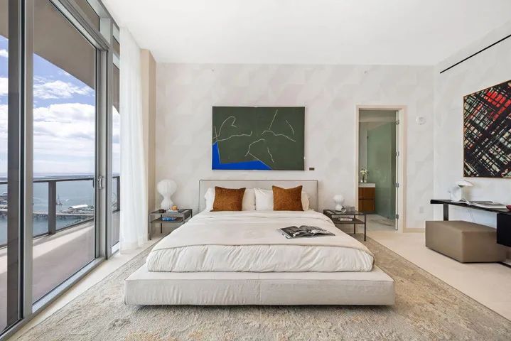 Floor-to-ceiling glass sliding doors, private balcony with metal railing, textured patterned wall treatment, and smooth-finish flooring