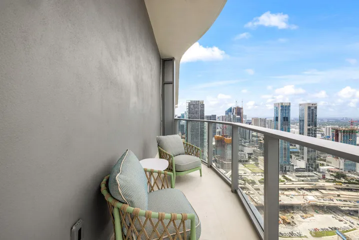 Covered balcony featuring a concrete floor, a solid exterior wall, and a metal railing with glass panels